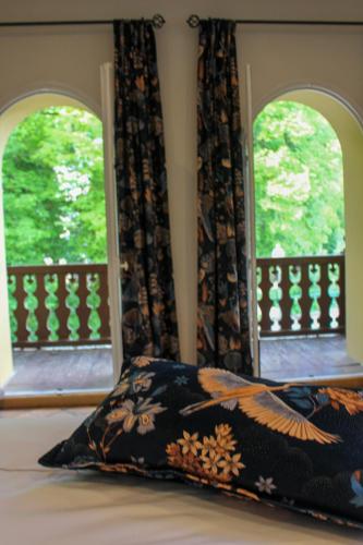 a bed with a pillow in front of two windows at Moulin de Fourges in Fourges