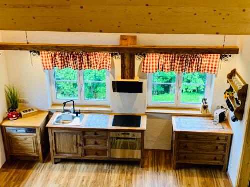 a kitchen with wooden cabinets and a sink and two windows at Bergheimat in Bad Goisern