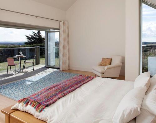 a bedroom with a large white bed and a patio at Downalong in Polzeath