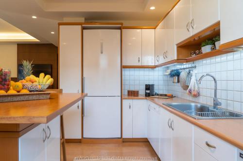a kitchen with white cabinets and a white refrigerator at Green Acre Villa in Karteros