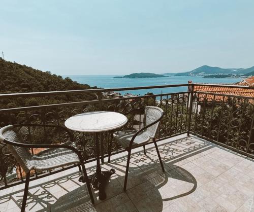 einen Tisch und Stühle auf einem Balkon mit Meerblick in der Unterkunft Apartments Mitrović Podličak in Sveti Stefan