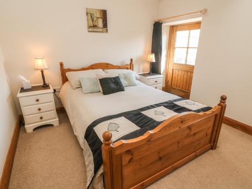 1 dormitorio con 1 cama de madera y 2 mesitas de noche en Old Hall Byre en Leyburn