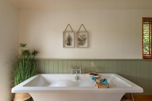 a white bath tub in a green bathroom at Higher Mapstone - A true retreat nestled in a private sanctuary on Dartmoor in Newton Abbot
