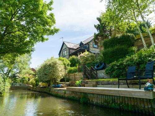 a house next to a river with trees at Waterfield House B&B in Dorchester