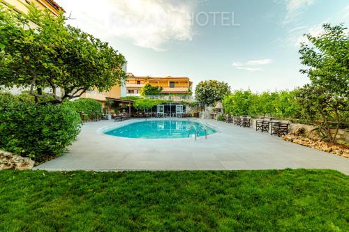 ein Schwimmbad in der Mitte eines Gartens in der Unterkunft Roxani Hotel in Ammoudara