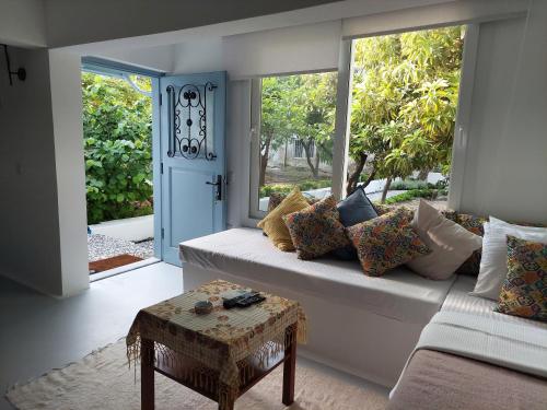 een woonkamer met een bank en een groot raam bij Mel’s Garden House in the heart of the city in Bodrum City