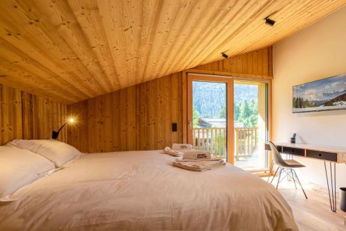 Schlafzimmer mit einem großen Bett, einem Schreibtisch und einem Fenster in der Unterkunft Chalet du Gouter - Chamonix All Year in Chamonix-Mont-Blanc