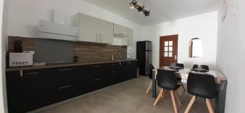 une cuisine avec des armoires en noir et blanc et une table dans l'établissement Le Repaire du Gabian, à Mireval