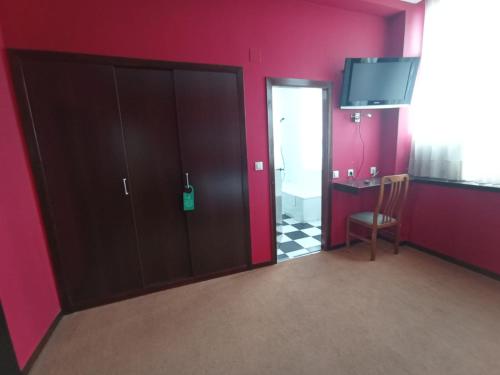 アビレスにあるHotel / Restaurante LA PEPAの紫の壁の客室で、ドア(椅子、テレビ付)が備わります。
