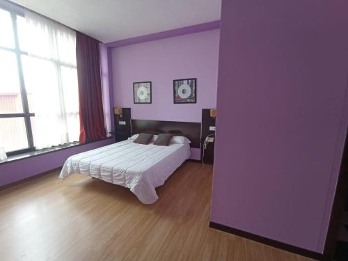 1 dormitorio con cama y pared púrpura en Hotel / Restaurante LA PEPA, en Avilés