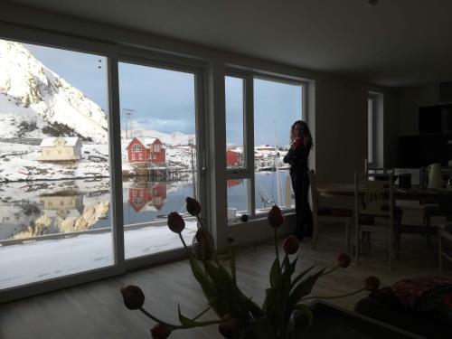 a woman standing in a room looking out of a window at Karlotte's apartment in Ballstad