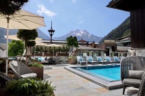 a resort with a pool and chairs and mountains at Hotel Neue Post in Mayrhofen