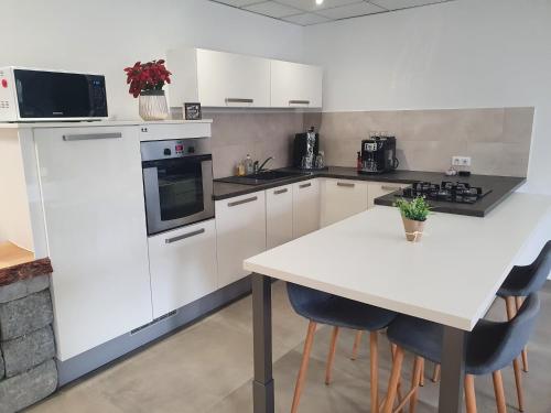 a kitchen with white cabinets and a white table with chairs at Chez Justine in Baccarat