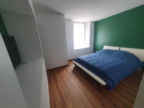 a bedroom with a blue bed and a green wall at Chez Justine in Baccarat