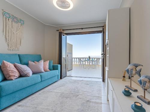 Cosy Seaview Apartment في سانتياغو ديل تيدي: غرفة معيشة مع أريكة زرقاء وشرفة