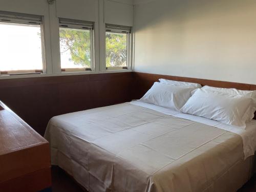 a bed with white sheets and pillows in a room with windows at AQUAMAR - Suite on the beach in Venice-Lido