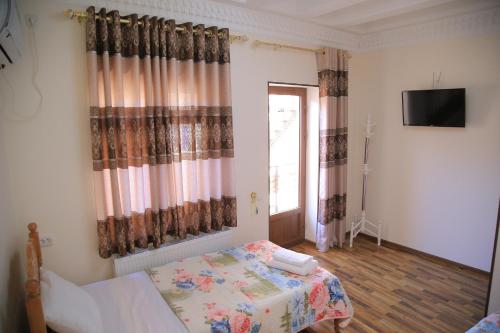 a bedroom with a bed and a television and a window at Hotel Mironshox in Bukhara