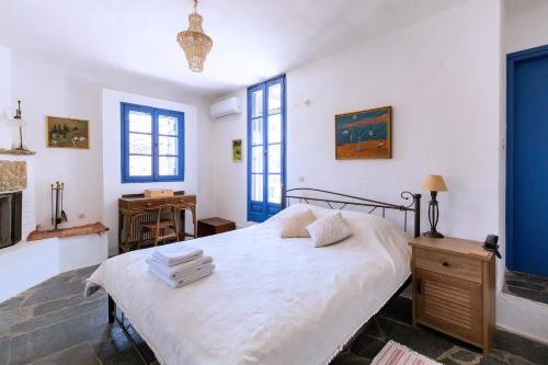 ein Schlafzimmer mit einem großen weißen Bett mit blauen Akzenten in der Unterkunft Traditional Village House On Kea in Milopótamos