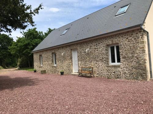 un bâtiment en pierre avec un banc devant lui dans l'établissement BlackBerry Cottage, à Lessay