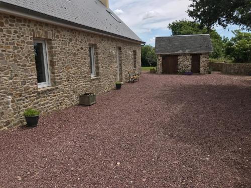 un bâtiment en briques avec un cimetière à côté de celui-ci dans l'établissement BlackBerry Cottage, à Lessay