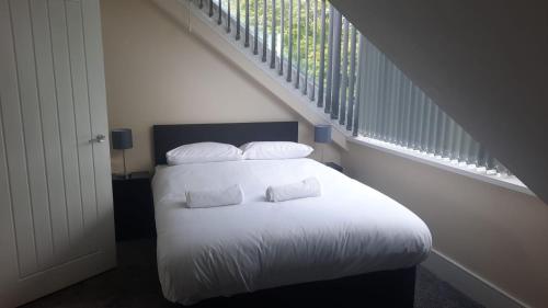 a white bed with two pillows sitting under a staircase at Alexander Apartments City North in Newcastle upon Tyne