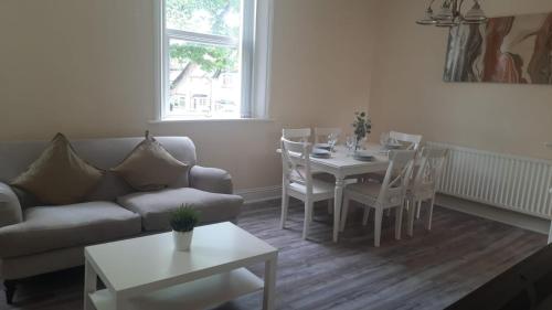 uma sala de estar com um sofá, uma mesa e cadeiras em Alexander Apartments City North em Newcastle upon Tyne