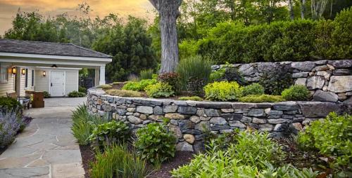 a stone retaining wall next to a house with a garden at Bedford Post Inn in Bedford