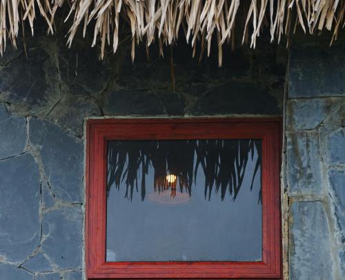 a reflection of a chandelier in a window of a stone building at Mộc Châu Peachy Garden in An Pon
