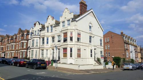 a large white building with cars parked in front of it at The Little Flat on the Corner in Cromer