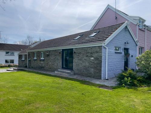 a stone house with a yard in front of it at Canllefaes Cottages in Cardigan