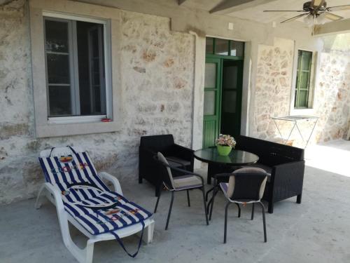 a patio with a table and chairs and a green door at Kastelanic apartman in Brbinj