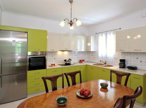 a kitchen with green cabinets and a wooden table at Frida's House in Kariá