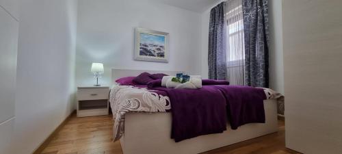 a bedroom with a bed with purple sheets and a window at Gea&Gala Apartments in Vantačići
