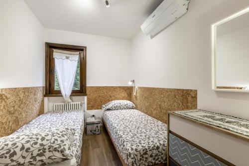 Zimmer mit 2 Betten, einem Spiegel und einem Fenster in der Unterkunft Des Alpes 2 in Canazei