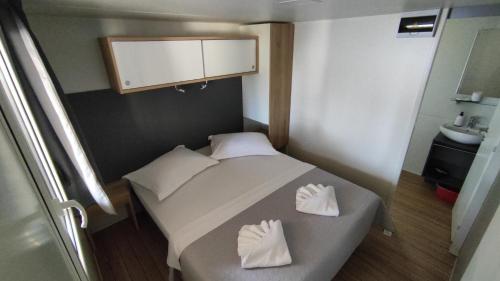 um pequeno quarto com uma cama e um lavatório em New Adria mobile Home - camp Vala em Orebić