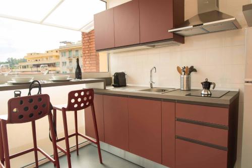 een keuken met een wastafel en een aanrecht met 2 stoelen bij Terrazza Giuliana in Rome