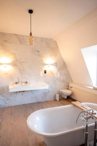 a bathroom with a white tub and a sink and a tub at Château de la Chapelle in Anthisnes