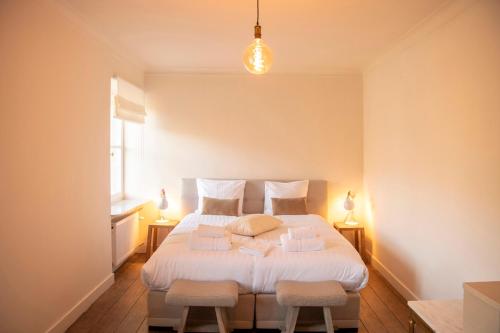 a bedroom with a large white bed with two stools at Château de la Chapelle in Anthisnes