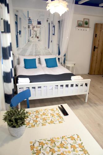 a bedroom with a white bed with blue pillows at Capitals Residence in Oświęcim