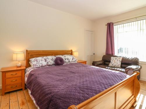 a bedroom with a bed and a couch and a window at Blue Skies Cottage in Arbroath
