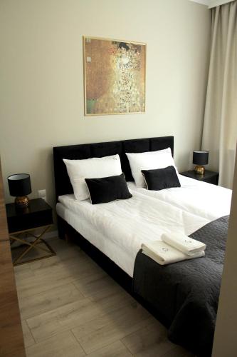 a bedroom with a large bed with white sheets and pillows at Capitals Residence in Oświęcim