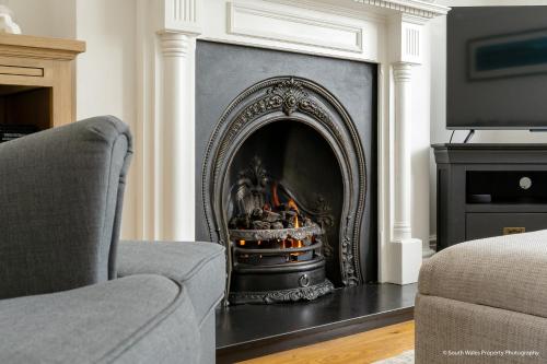 a fireplace in a living room with a chair at 6 Woodville in The Mumbles