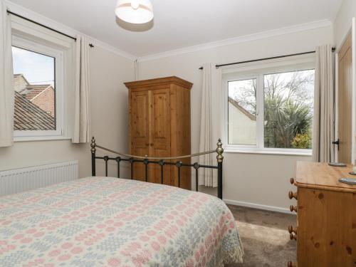 a bedroom with a bed and two windows at Long Batch Cottage in Shepton Mallet