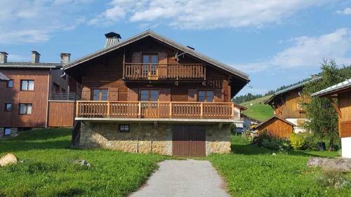 a large wooden house with a balcony on top of it at CHALET FAMILIAL AU PIED DES PISTES ET COMMERCES in Cohennoz