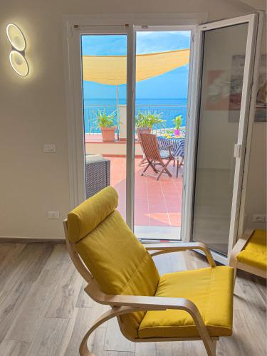 a yellow chair in a room with a view of the ocean at Vista Mare Borgo Peri in Imperia