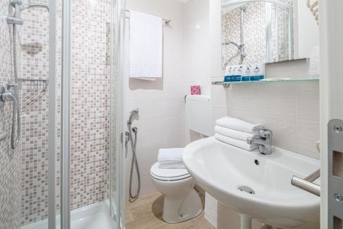 a bathroom with a toilet and a sink and a shower at Hotel Pigalle in Lido di Jesolo