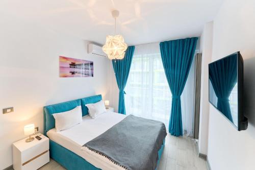 a bedroom with a blue and white bed and a window at Rainbow sea view apartment Spa n Pool resort - parking in Mamaia