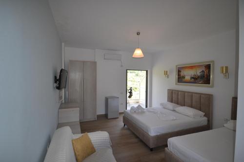 1 dormitorio con 2 camas y sofá en Bujtina Eleni, en Himare