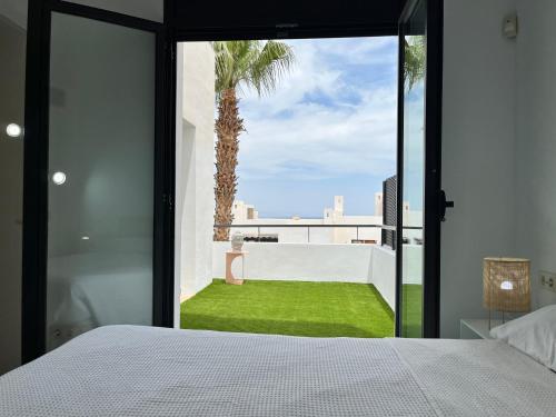 a bedroom with a white bed and a palm tree at Flamingo Mojácar - Precioso 2 dormitorios en Macenas Resort, con vistas al mar y piscina in Mojácar