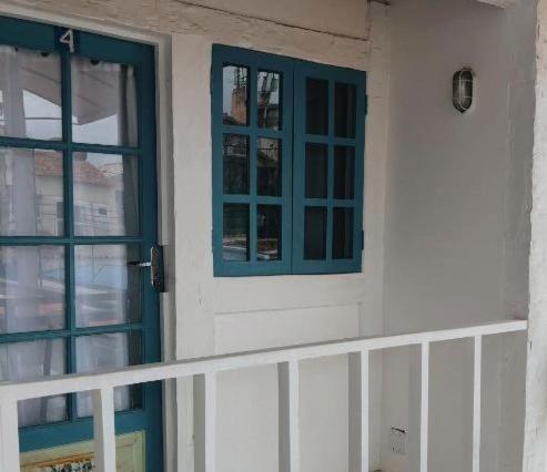 a white house with blue windows and a porch at Casa da Lua Buzios in Búzios